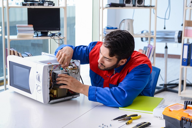 Young repairman fixing and repairing microwave oven